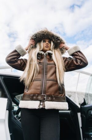 Kożuch damski w brązowym kolorze z futrzanym kapturem i paskiem w talii, idealny na zimowe dni