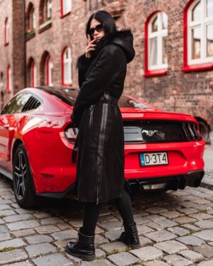 Czarny kożuch damski z kapturem, futrzanym wykończeniem i paskiem w talii, idealny na zimowe dni