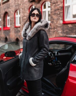 Kożuch damski w kolorze czarnym z futrzanym kapturem i białymi mankietami, idealny na zimowe dni